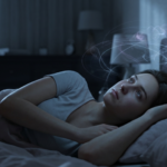 Person staring at the ceiling in the dark, struggling with sleep issues and racing thoughts